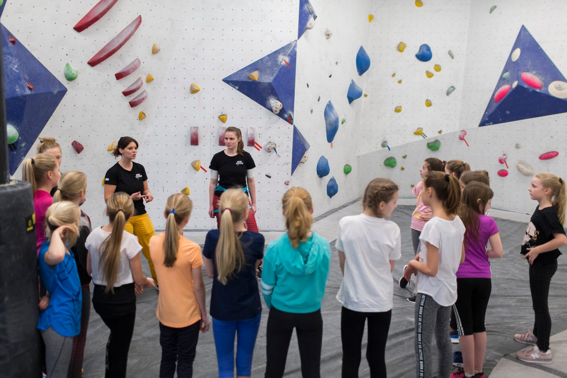 Trainerinnen erklären Kids etwas im Boulderbereich